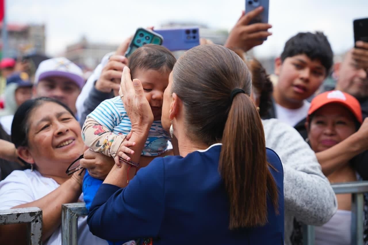 Claudia Sheinbaum saluda a una familia entre asistentes al acto en la Ciudad de México