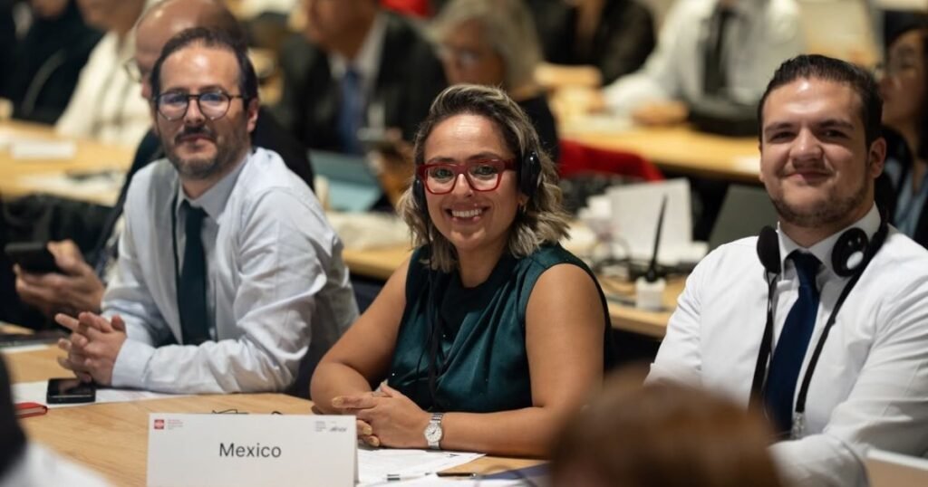 Tres personas sentadas en una reunión con una identificación de México visible al frente
